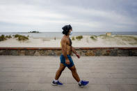 FILE - In this March 17, 2020 file photo, a man gets some exercise along the seaside in Montevideo, Uruguay. Many countries in Latin American and the Caribbean saw their first cases of novel coronavirus arrive with jetsetting members of the elite returning from vacations or work trips to Europe and the United States. (AP Photo/Matilde Campodonico, File)