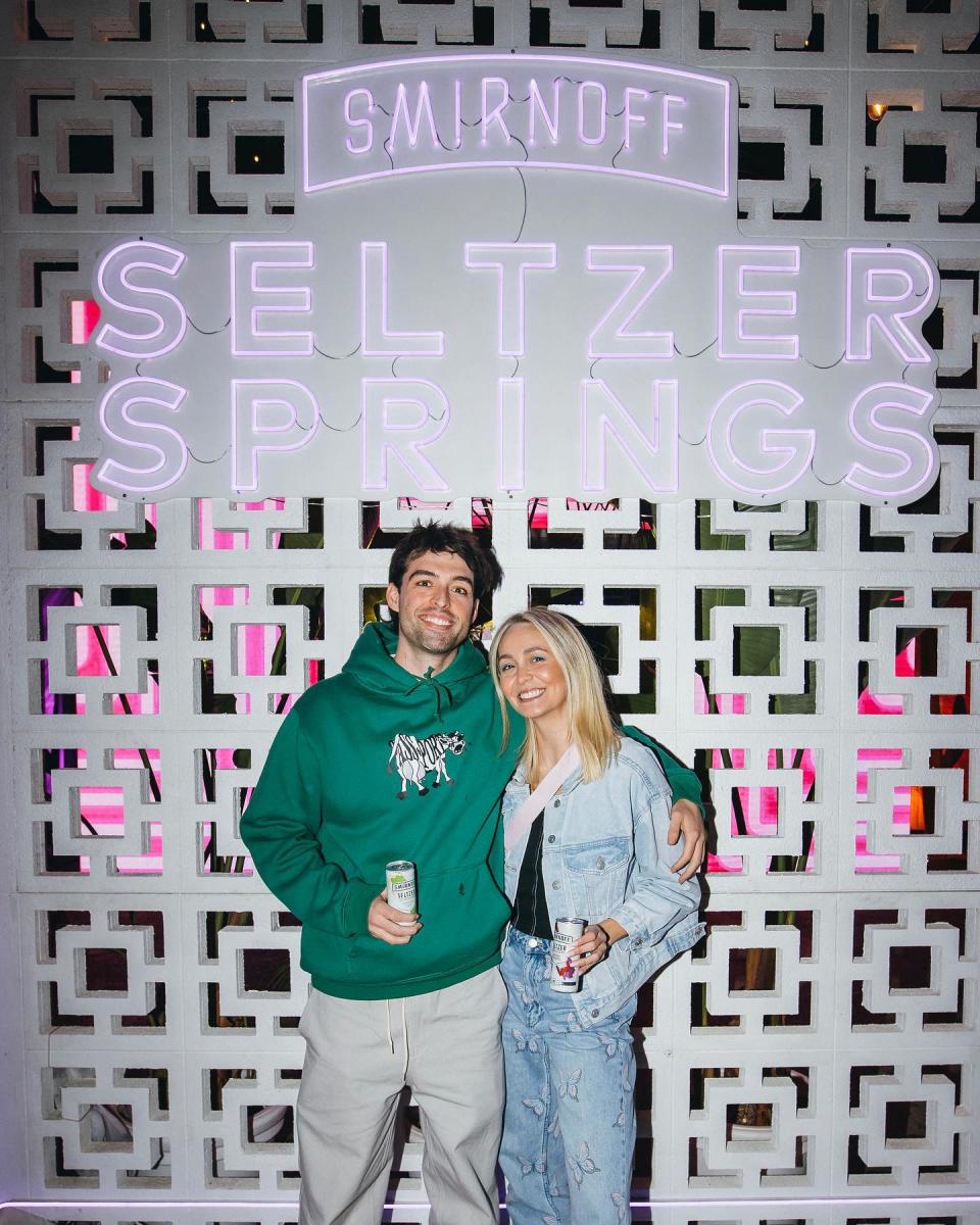 Ollie Skelton and Tahnee Cook in front of a Smirnoff sign 