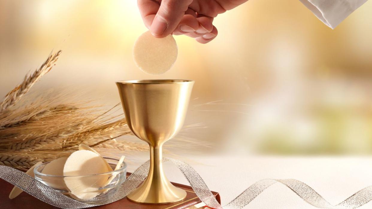 priest dipping host in wine at eucharist,spain