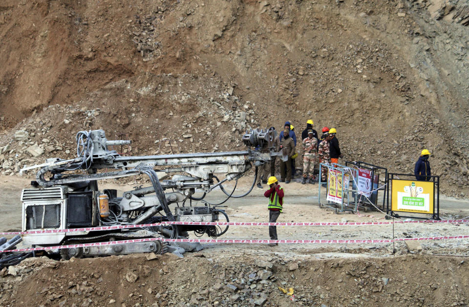 Rescuers stand near heavy machinery at the site of an under-construction road tunnel that collapsed in mountainous Uttarakhand state, India, Friday, Nov. 17, 2023. Rescuers drilled deeper into the rubble of a collapsed road tunnel in northern India on Friday to fix wide pipes for 40 workers trapped underground for a sixth day to crawl to their freedom. (AP Photo)
