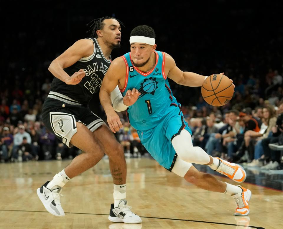 Phoenix Suns guard Devin Booker (1) is defended by San Antonio Spurs guard Tre Jones (33) during the second quarter at Footprint Center in Phoenix on April 4, 2023.