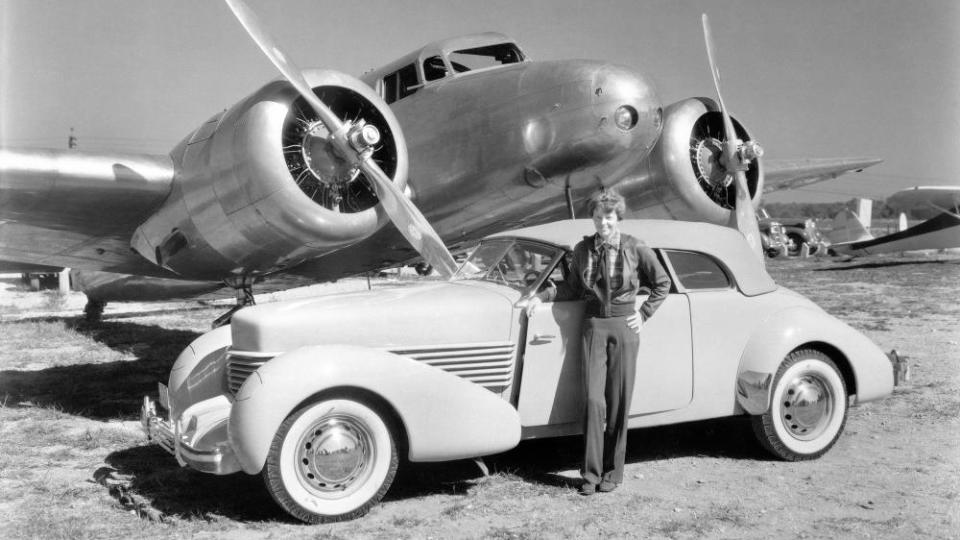 Amelia Earhart stands in front of both her 1937 Cord 812 Phaeton Convertible and her Lockheed Electra 10E aircraft.