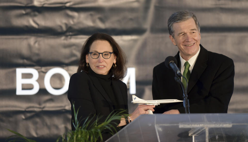 North Carolina Gov. Roy Cooper receives a model of Boom Supersonic's Overture jet from Boom's President and Chief Business Officer Kathy Savitt during an announcement, Wednesday, Jan. 26, 2022 that the aviation company will build its supersonic jet at Piedmont Triad International Airport in Greensboro, N.C. The company said it will employ more than 1700 people by the end of the decade. (Walt Unks/Winston-Salem Journal via AP)