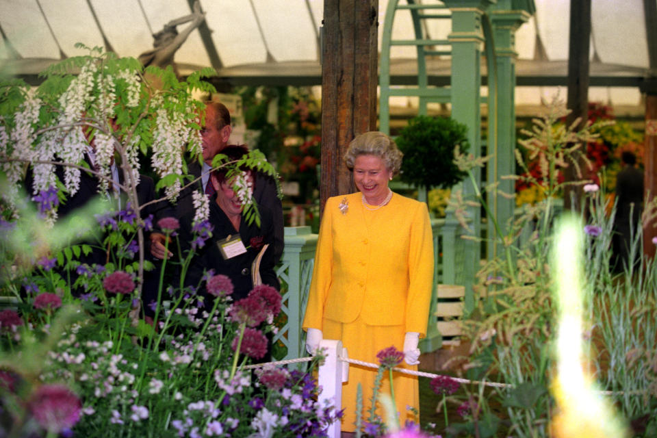 <p>Con un llamativo conjunto amarillo y rodeada de flores, así captaron a Su Majestad en 1994. "Los jardines mediterráneos se hicieron populares en los años 90 y esta década también supuso la llegada de los jardines conceptuales, jardines que existen para expresar un tema", expone la web de Chelsea Flower Show. (Foto: Martin Keene / Getty Images)</p> 