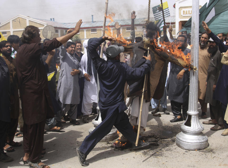 A Pakistani protester beats a burning effigy of Indian Prime Minister Narendra Modi during a protest in Quetta, Pakistan, Thursday, Aug. 15, 2019. Pakistan's prime minister has questioned the silence of world community over recent change in the status of Indian-administered sector of Kashmir by New Delhi and lingering imposition of security clampdown which deprived Kashmiri people of their basic rights. (AP Photo/Arshad Butt)