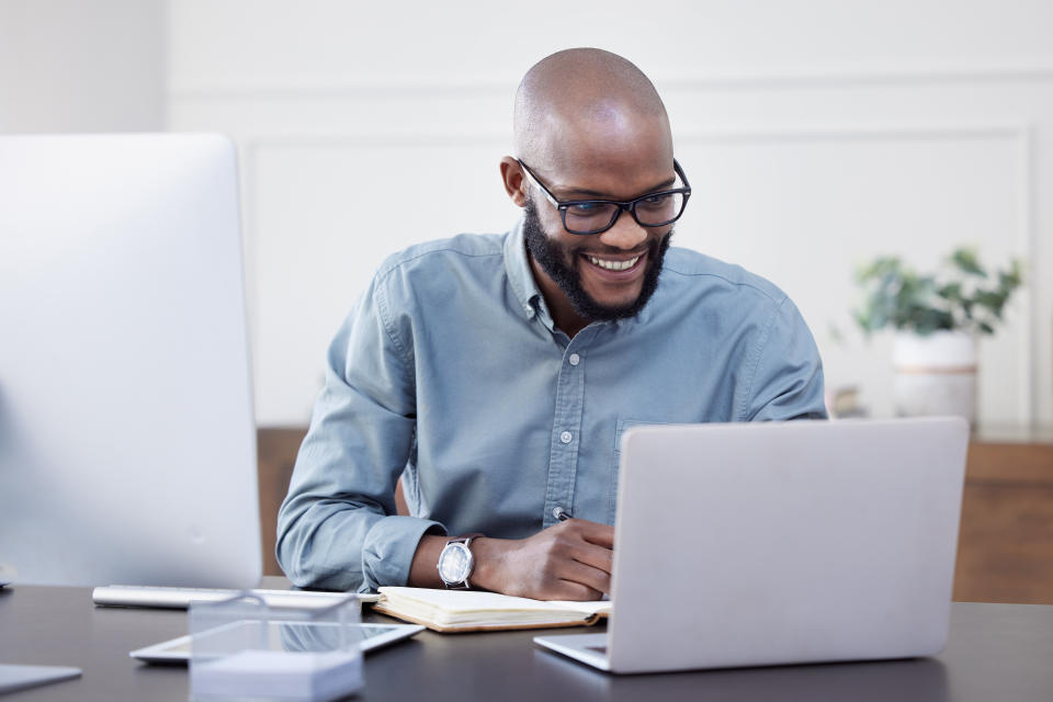Happy black man working on laptop in an office.