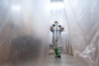In this photo taken on Monday, May 4, 2020, a doctor, wearing a special suit to protect against coronavirus, walks through a corridor at an intensive care unit at a regional hospital in Chernivtsi, Ukraine. Ukraine's troubled health care system has been overwhelmed by COVID-19, even though it has reported a relatively low number of cases. (AP Photo/Evgeniy Maloletka)