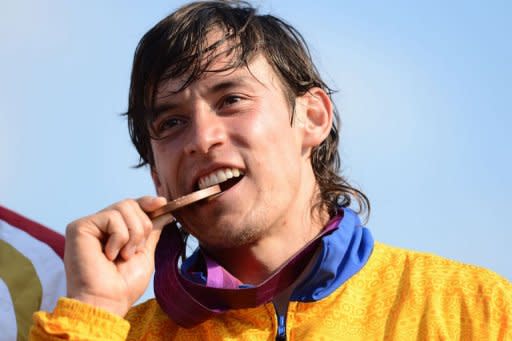 El colombiano Carlos Mario Oquendo muerde la medalla de bronce conseguida este viernes en la final de la BMX olímpica, disputada en el Parque Olímpico de Londres. (AFP | Carl de Souza)