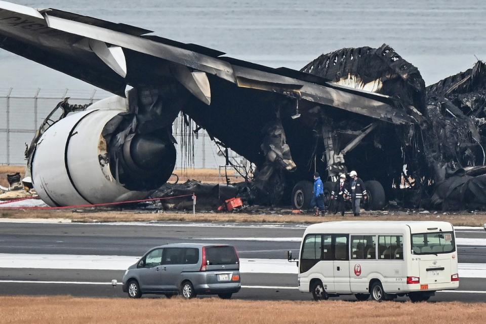 Officials look at the burnt wreckage of a Japan Airlines (JAL) passenger plane on the tarmac at Tokyo International Airport at Haneda (AFP via Getty Images)