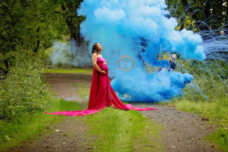 Pregnant woman stands in front of blue smoke