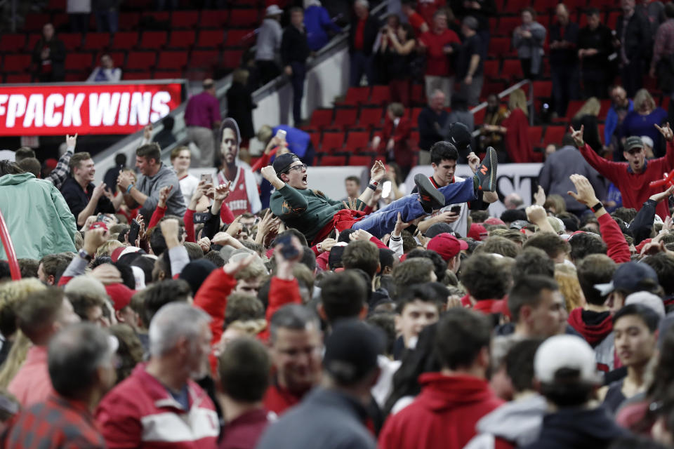 North Carolina State fans storm the court following the team's win over Duke in an NCAA college basketball game in Raleigh, N.C., Wednesday, Feb. 19, 2020. (AP Photo/Gerry Broome)