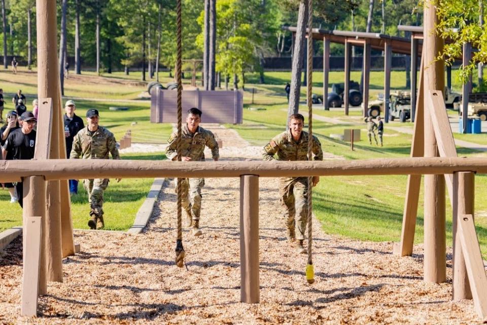 US Soldiers sprint toward swinging ropes to clear a wooden obstacle