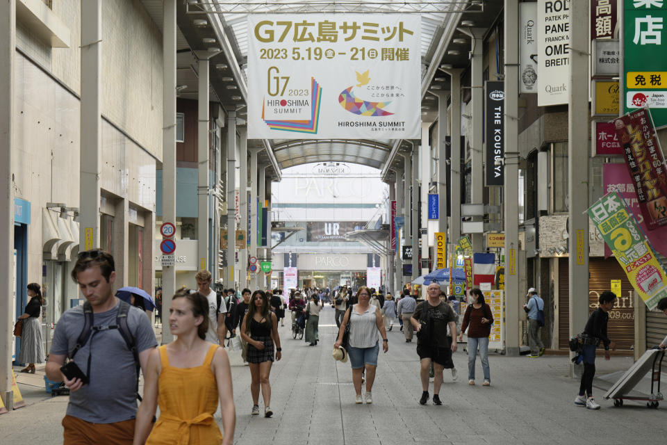 People walk under a banner in a shopping street, announcing the upcoming Group of Seven nations' meetings in Hiroshima, western Japan, Wednesday, May 17, 2023. The G-7 summit starts Friday. (AP Photo/Hiro Komae)