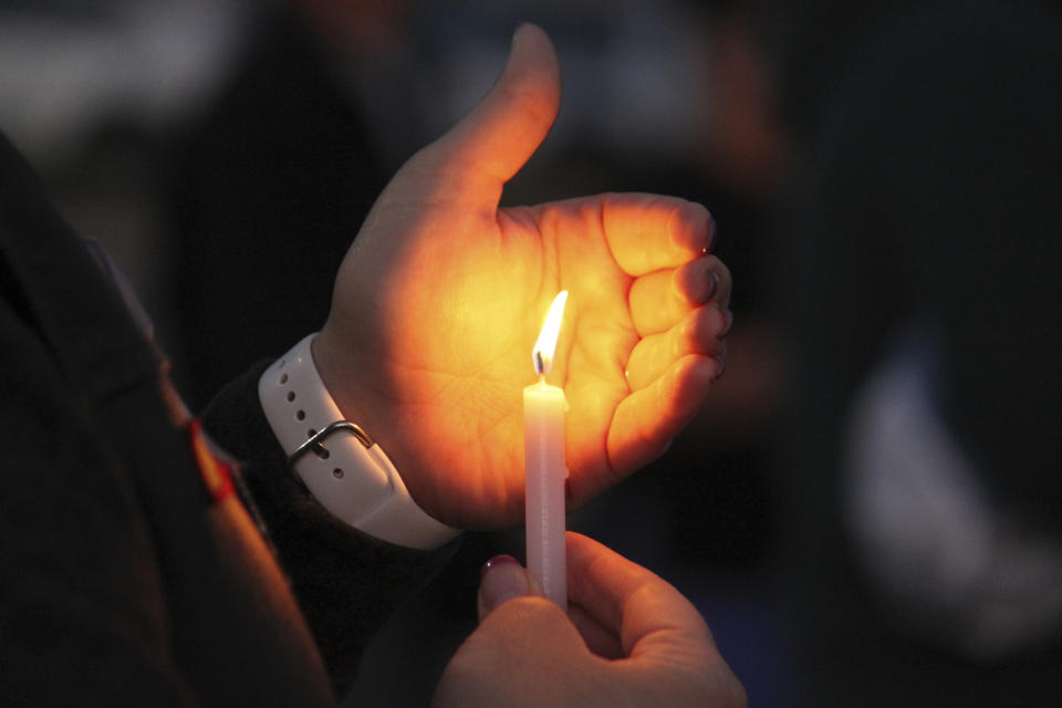 A community member holds a candle during a prayer vigil at Hills Church, Monday, May 15, 2023, in Farmington, N.M. Authorities said an 18-year-old man roamed through the community firing randomly at cars and houses Monday, killing three people and injuring six others including two police officers before he was killed. (AP Photo/Susan Montoya Bryan)