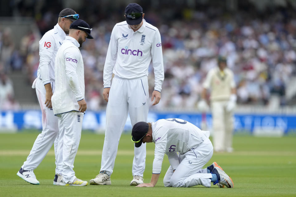 England's players gather around teammate Ollie Pope after he fell while fielding during day one of the second Ashes Test cricket match at Lord's Cricket Ground, London, England, Wednesday, June 28, 2023. (AP Photo/Kirsty Wigglesworth)