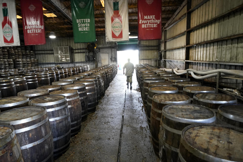 David Botkin, a mash warehouse technician, walks among barrels of Tabasco pepper mash that is being aged, at the McIlhenny Company on Avery Island, La., Tuesday, April 27, 2021. The company has been brewing Tabasco Sauce since 1868 on Avery Island — the tip of a miles-deep column of salt — and now fills up to 700,000 bottles a day, selling them in 195 countries and territories. (AP Photo/Gerald Herbert)