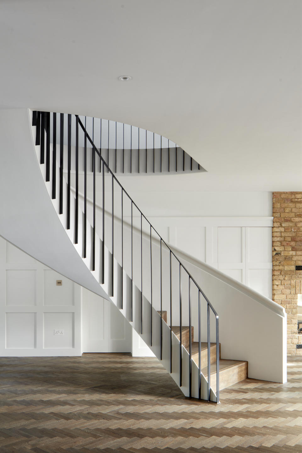 curved white staircase with black railings and wood steps