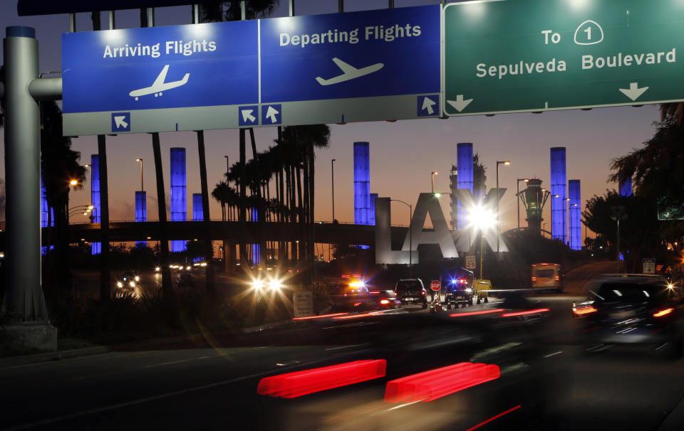 FILE - In this Nov. 2, 2013 file photo lighted pylons line the entrance to Los Angeles International Airport in Los Angeles. At the end of the month, travelers will not be able to hail a rideshare or taxi outside terminals at Los Angeles International Airport. LAX announced Friday, Oct. 4, 2019, that travelers will instead have to take shuttles or walk to a special location outside the central terminal area where they can be picked up. (AP Photo/Reed Saxon,File)