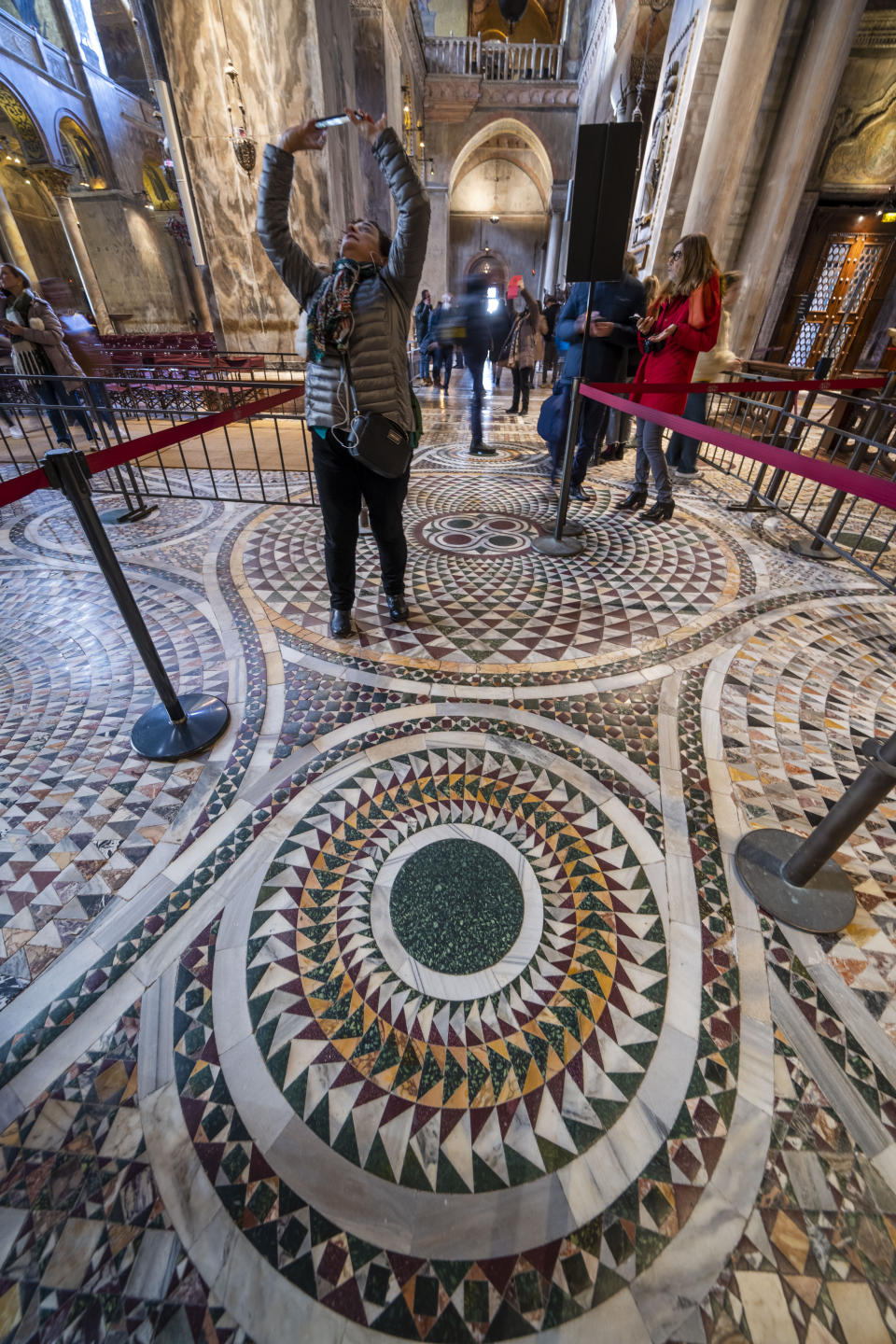 Belt barriers limit visitors' circulation on the fragile marble mosaics of the floor of St. Mark's Basilica in Venice, northern Italy, Wednesday, Dec. 7, 2022. Glass barriers that prevent seawater from flooding the 900-year-old iconic St Mark's Basilica during high tides have been recently installed around it. St. Mark's Square is the lowest-laying city area and frequently ends up underwater during extreme weather. (AP Photo/Domenico Stinellis)