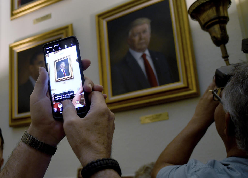 People take photos of President Donald Trump's portrait hanging in the Colorado Capitol after an unveiling ceremony Thursday, Aug. 1, 2019, in Denver. Colorado Republicans raised more than $10,000 through a GoFundMe account to commission the portrait, which was painted by Sarah Boardman, an artist who also produced the Capitol's portrait of President Barack Obama. (AP Photo/Thomas Peipert)