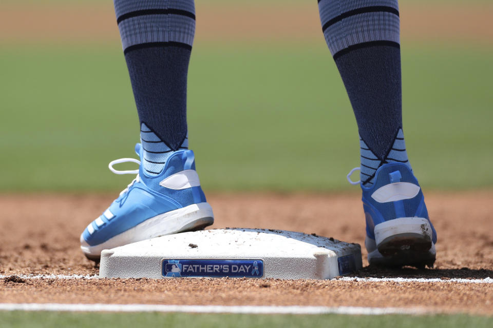 San Diego Padres' Eric Hosmer wears blue cleats while standing on first base adorned with a Father's Day sticker during a baseball game against the Cincinnati Reds, Sunday, June 20, 2021, in San Diego. (AP Photo/Derrick Tuskan)