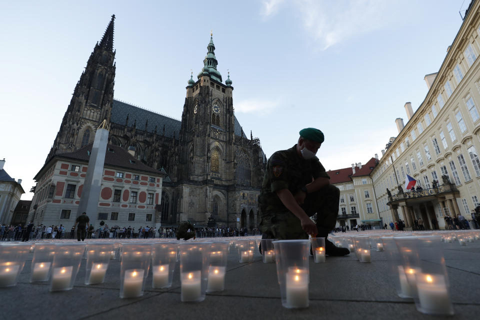 A soldier lights up a candle to commemorate victims of the COVD-19 pandemic at the Prague Castle in Prague, Czech Republic, Monday, May 10, 2021. The Czech Republic is massively relaxing its coronavirus restrictions as the hard-hit nation pays respect to nearly 30,000 dead. (AP Photo/Petr David Josek)