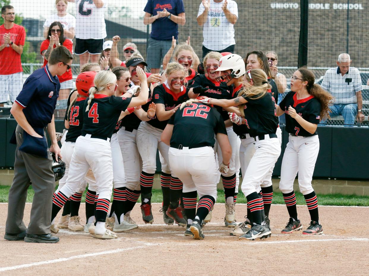Grace Frame is mobbed by teammates at home plate after hitting a grand slam in the third inning of Crooksville's 12-0 win against Portsmouth in a Division III district final on Saturday at Unioto High School in Chillicothe. Frame had a team-high three hits as the Ceramics reached their first regional since 2012.