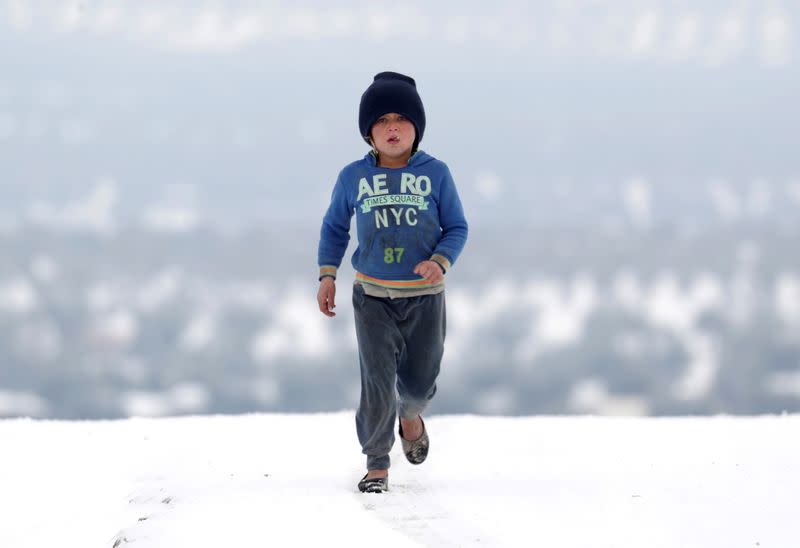 Una niña desplazada camina sobre la nieve en un campamento improvisado en Azaz, Siria