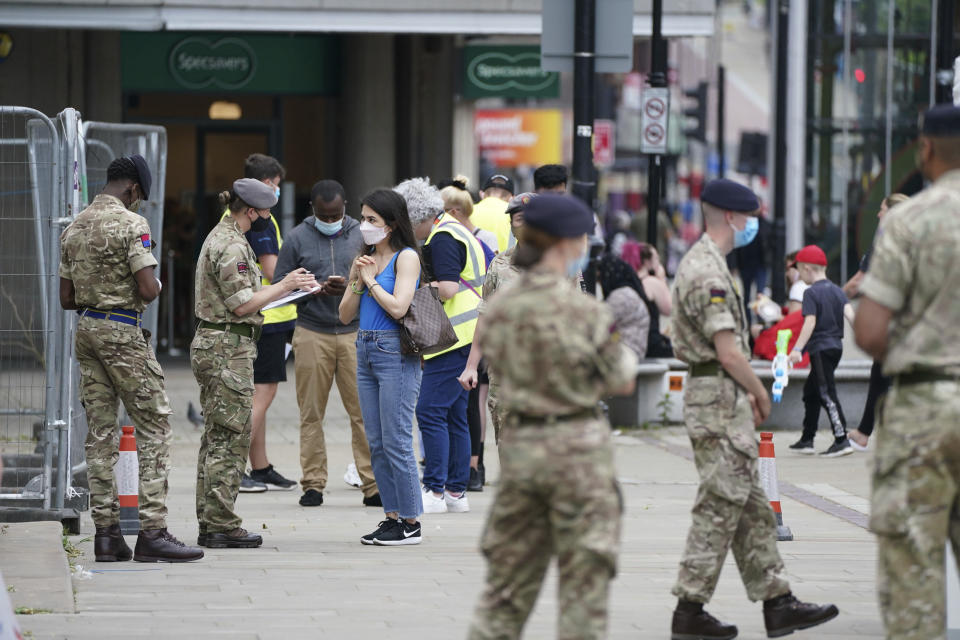 Members of the Armed Forces speak to people, outside a mobile COVID-19 vaccination centre outside Bolton Town Hall, in Bolton, England, Wednesday, June 9, 2021, where case numbers of the Delta variant first identified in India have been relatively high. (Peter Byrne/PA via AP)