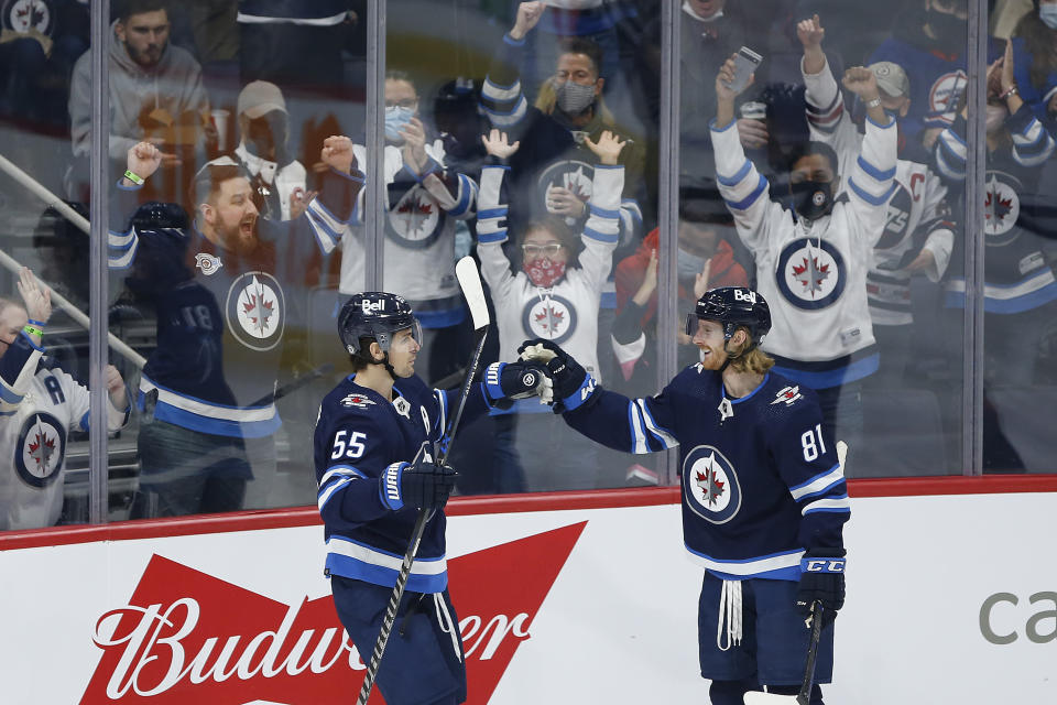 Winnipeg Jets' Mark Scheifele (55) and Kyle Connor (81) celebrate Scheifele's goal on New Jersey Devils goaltender Jonathan Bernier during the first period of an NHL hockey game Friday, Dec. 3, 2021, in Winnipeg, Manitoba. (John Woods/The Canadian Press via AP)