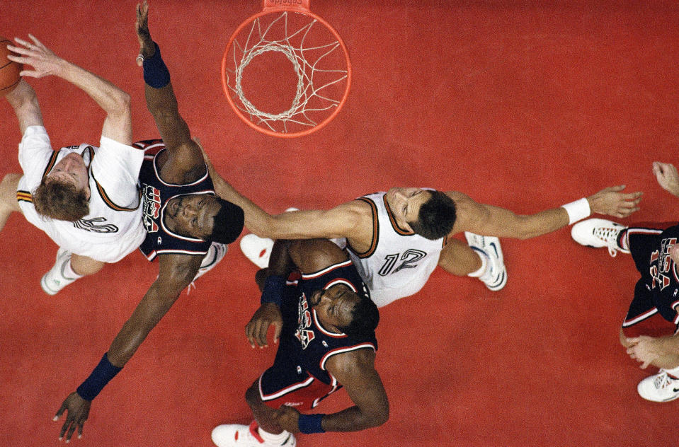 FILE - Germany's Michael Jackel, left, tries to get past the USA's Patrick Ewing as teammate Karl Malone holds off Germany's Hans Gnad, right, during their preliminary game at the 1992 Summer Olympic, July 29, 1992, in Barcelona. The "Dream Team" with the first U.S. Olympic men's basketball team to field active NBA players rolls past Croatia 117-85 for the gold medal at the 1992 Barcelona Games. The Americans demolish the field. (AP Photo, File)