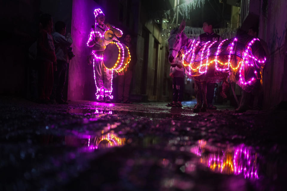FILE - Mohammed El-Dahshan, 38-year-old "mesaharati," or dawn caller, accompanies his donkey wrapped with colored led lights to wake Muslims up for a meal before sunrise, during the Islamic holy month of Ramadan, in the Delta city of Dikernis, Egypt, about 93 miles (150 kilometers) north of Cairo, early Wednesday, April 12, 2023. Each night, El-Dahshan, sets out after midnight with his donkey banging his drum, chanting traditional religious phrases and calling out on residents by name to wake them in time for the vital pre-dawn meal known as "suhoor". (AP Photo/Amr Nabil, File)