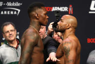 UFC middleweight champion Israel Adesanya, front left, of Nigeria, and challenger Yoel Romero, right, of Cuba, face off during a ceremonial weigh-in for UFC 248 at T-Mobile Arena in Las Vegas, Friday, March 6, 2020. UFC president Dana White keeps the fighters separated. Adesanya will defend his title against Romero at the arena on Saturday, March 7. (Steve Marcus/Las Vegas Sun via AP)