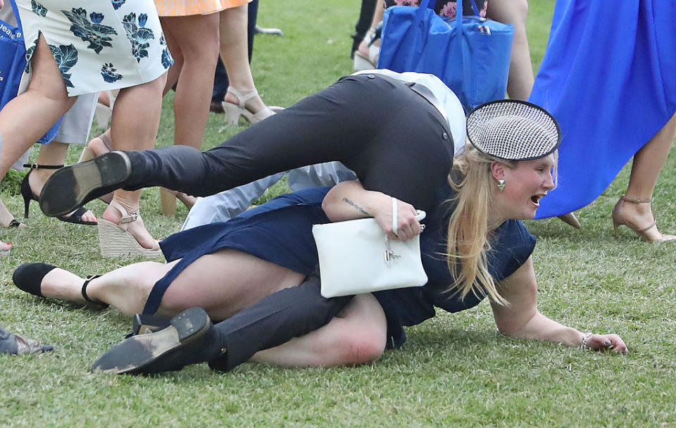 Racegoers tangled up on the grass during the 2016 Melbourne Cup at Flemington Racecourse.