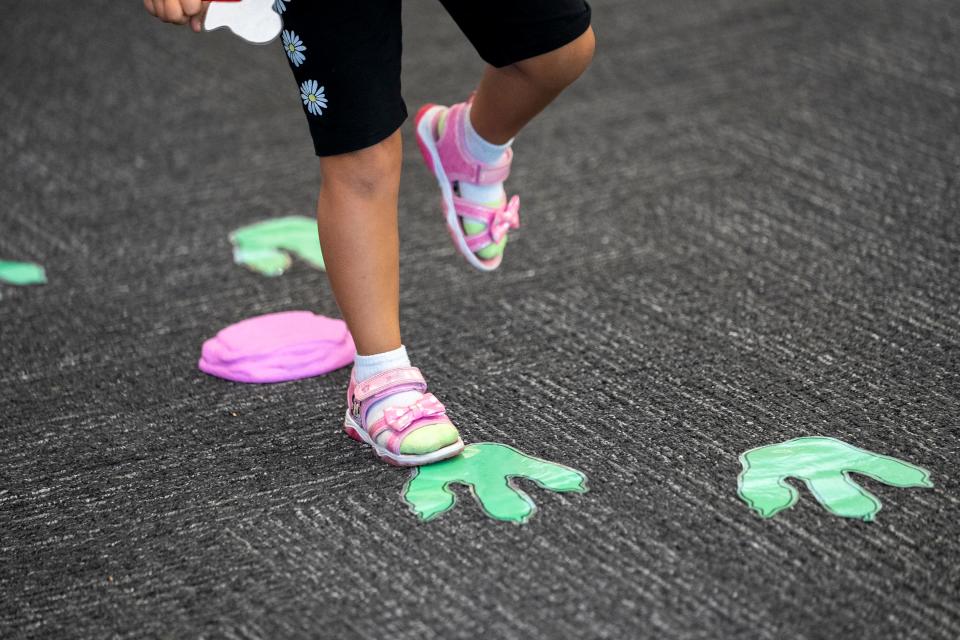 Sep 13, 2023; Gahanna, Ohio, USA;  (from R) Addison Leslie, 5, skips along dinosaur tracks during Family Story Hour at the Gahanna Branch of the Columbus Metropolitan Library. 