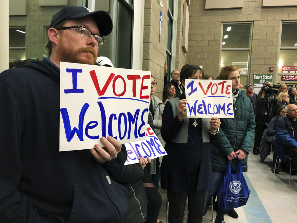 FILE - In this Dec. 9. 2019, file photo, residents in support of continued refugee resettlement hold signs at a meeting in Bismarck, N.D. A federal judge agreed Wednesday, Jan. 15, 2020, to block the Trump administration from enforcing an executive order allowing state and local government officials to reject refugees from resettling in their jurisdictions. U.S. District Judge Peter Messitte in Maryland issued a preliminary injunction requested by three national refugee resettlement agencies that sued to challenge the executive order. (AP Photo/James MacPherson, File)