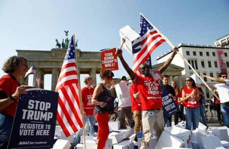 Campaigners pose with 'Stop Trump' signs in front of the Brandenburg Gate to urge Americans living abroad to register and vote in Berlin, Germany, September 23, 2016. REUTERS/Axel Schmidt