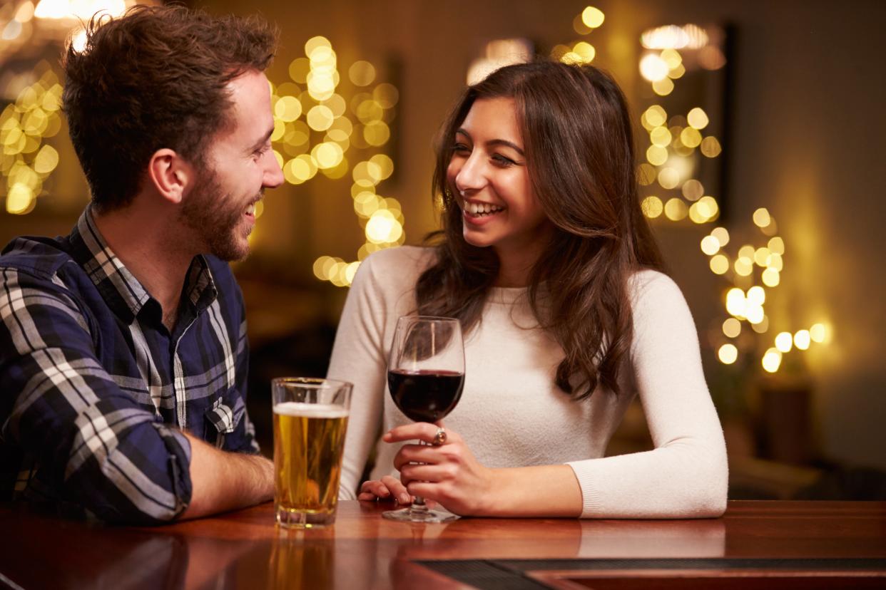 Couple smiling over drinks in bar to portray speed dating (Getty Images)