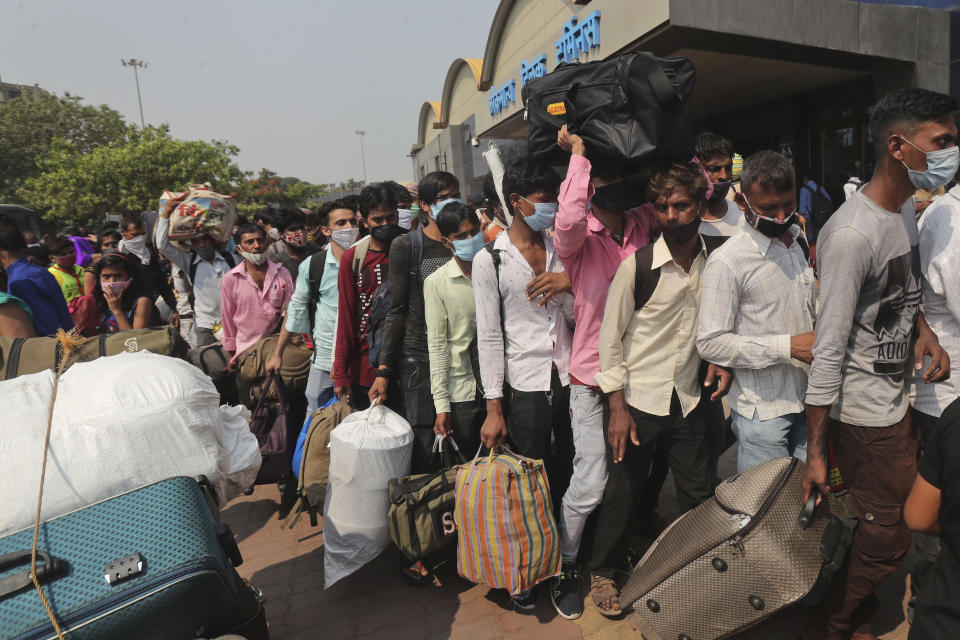 People wearing masks as a precaution against the coronavirus stand in queues to board trains at Lokmanya Tilak Terminus in Mumbai, India, Wednesday, April 14, 2021. India has been overwhelmed by hundreds of thousands of new coronavirus cases daily, bringing pain, fear and agony to many lives as lockdowns have been placed in Delhi and other cities around the country. (AP Photo/Rafiq Maqbool)