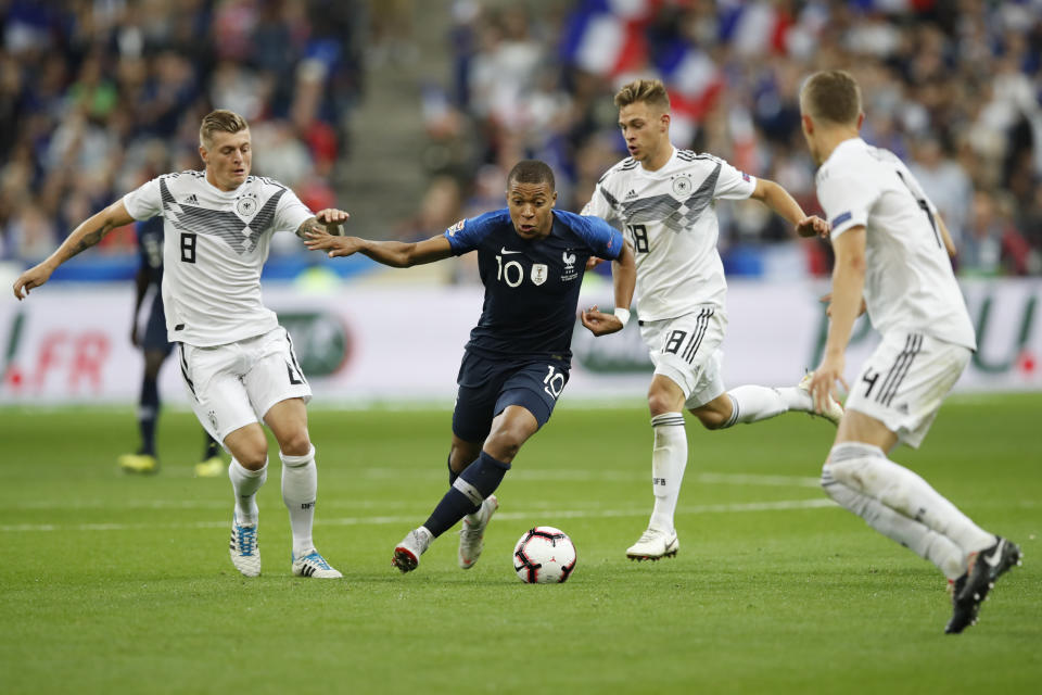 France's Kylian Mbappe, 2nd left, challenges for the ball with Germany's Toni Kroos, left, and Germany's Toni Kroos while Germany's Matthias Ginter, right, looks on during a UEFA Nations League soccer match between France and Germany at Stade de France stadium in Saint Denis, north of Paris, Tuesday, Oct. 16, 2018. (AP Photo/Christophe Ena)