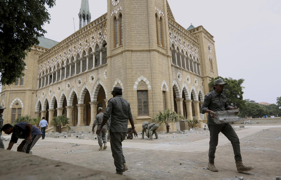 Workers for Karachi Municipal Corporation remove an artwork of concrete tombstones marking the number of "extrajudicial killings", at Frere Hall in Karachi, Pakistan, Tuesday, Oct. 29, 2019. A Pakistani artist says authorities closed her exhibition in Karachi that sought to denounce police raids led by an infamous officer that had killed hundreds of people. (AP Photo/Fareed Khan)