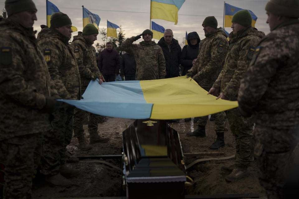 FILE - Ukrainian soldiers hold their national flag over the coffin of comrade Dmytro Kyrychenko, during his funeral in Bucha, outskirts of Kyiv, Ukraine, Friday, Dec. 23, 2022. Quantifying the toll of Russia’s war in Ukraine remains an elusive goal a year into the conflict. Estimates of the casualties, refugees and economic fallout from the war produce an complete picture of the deaths and suffering. Precise figures may never emerge for some of the categories international organizations are attempting to track. (AP Photo/Felipe Dana, File)