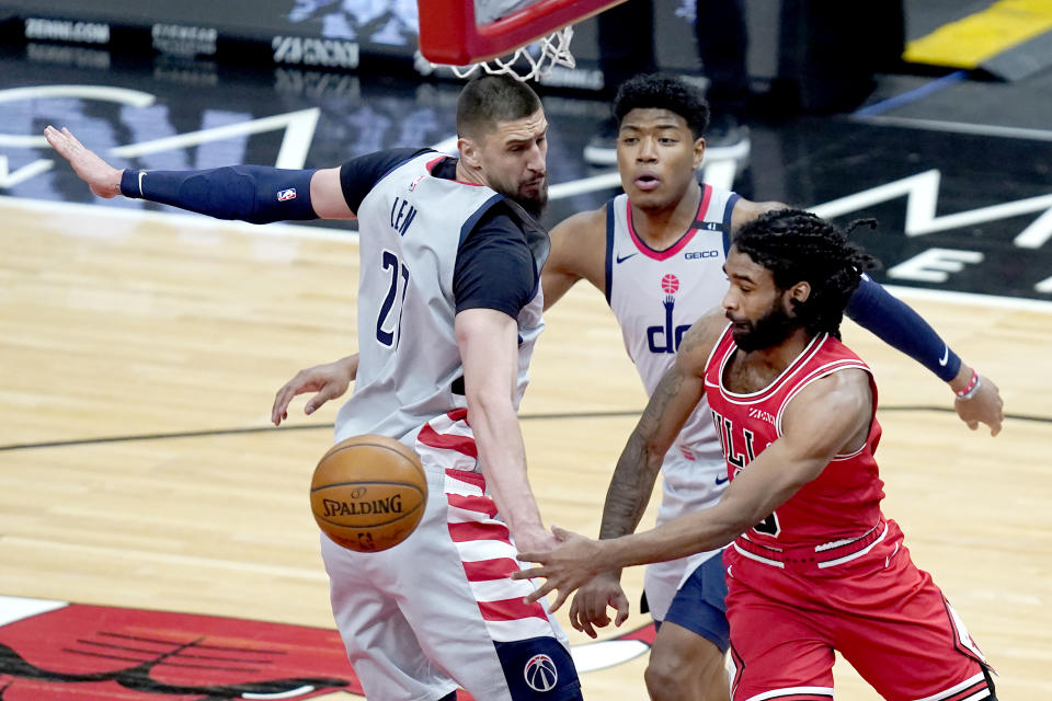Chicago Bulls' Coby White passes the ball under the basket past the defense of Washington Wizards' Alex Len as Rui Hachimura watches during the first half of an NBA basketball game Monday, Feb. 8, 2021, in Chicago. (AP Photo/Charles Rex Arbogast)