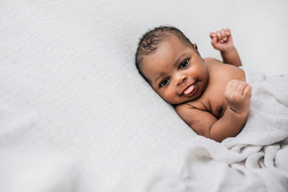 beautiful african american newborn little boy just a few weeks old swaddled in a cream colored soft blanket with copy space