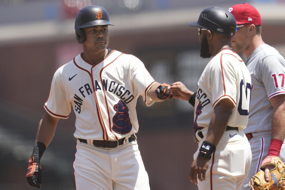 San Francisco Giants' LaMonte Wade Jr., left, is congratulated by first base coach Antoan Richardson after hitting a single against the Philadelphia Phillies during the first inning of a baseball game in San Francisco, Saturday, June 19, 2021. The Giants are wearing San Francisco Sea Lions jerseys to honor Juneteenth on African American Heritage Day. (AP Photo/Jeff Chiu)