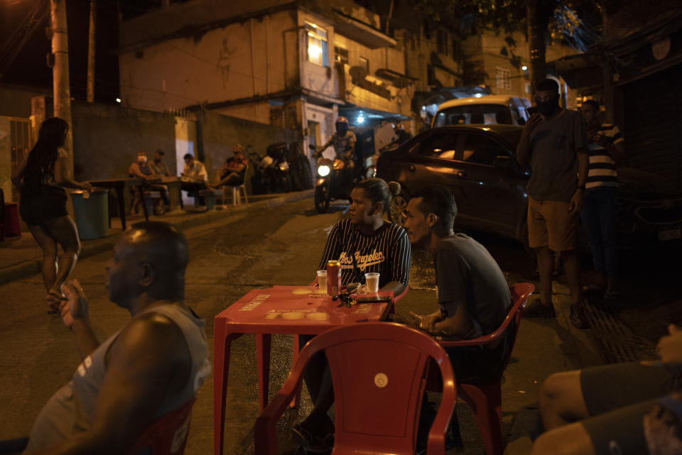 Residents watch members of "Tempero de Criola" perform in the Turano favela amid the new coronavirus pandemic, in Rio de Janeiro, Brazil, Friday, June 19, 2020. A group of musicians playing Samba offered a small concert to the residents of Turano favela, most of whom remain quarantined to curb the spread of COVID-19. Residents could watch the performance from their windows, balconies or via internet. (AP Photo/Silvia Izquierdo)