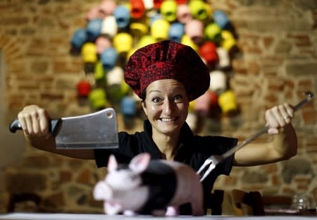 Italian chef Cristina Palanti poses with a meat cleaver and cooking fork hovering over a plastic pig figurine at the "L'e'Maiala" restaurant in Florence in this October 6, 2012 file photo. REUTERS/Alessandro Bianchi/files