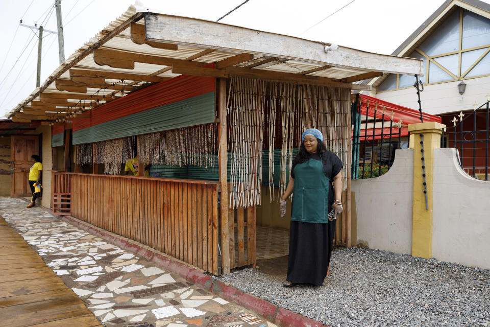 Anita Akpeere, who uses her mobile phone to run her business, stands outside her restaurant in Accra, Ghana, Tuesday, April 23, 2024. ( AP Photo/ Misper Apawu)