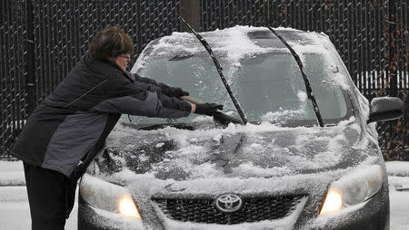 A woman scrapes ice from her car's windshield in the parking lot of a grocery store in Minneapolis, November 10, 2014. REUTERS/Eric Miller