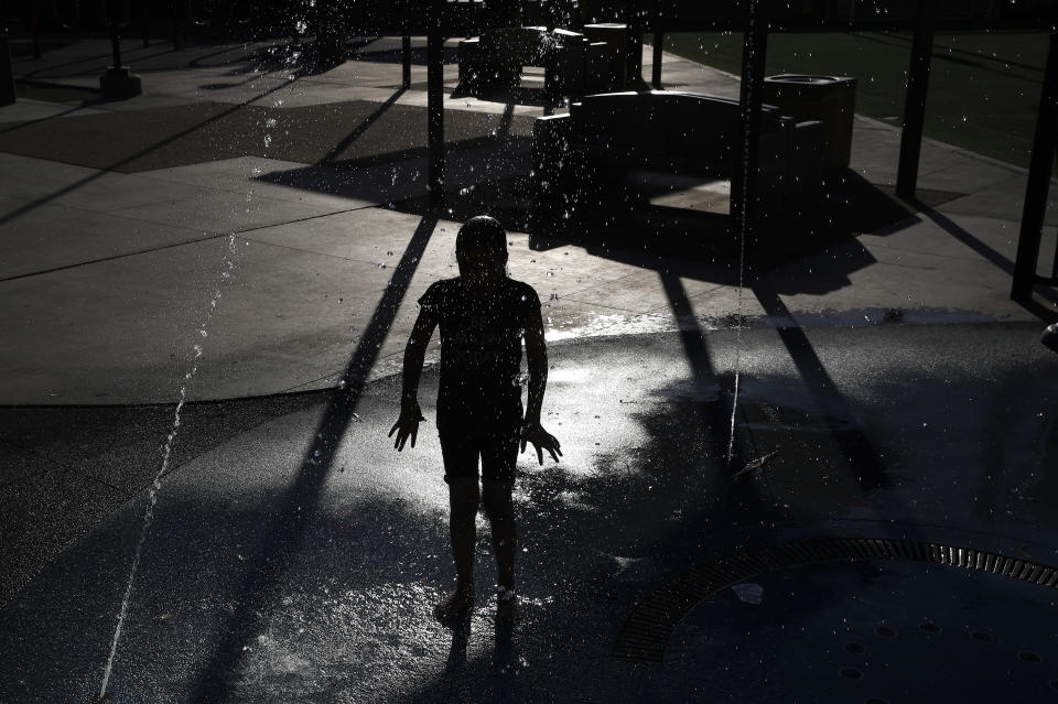 Ashley Mendoza cools off in a water feature at a park, Tuesday, July 24, 2018, in Las Vegas. The National Weather Service has issued an excessive heat warning for the Las Vegas valley. (AP Photo/John Locher)